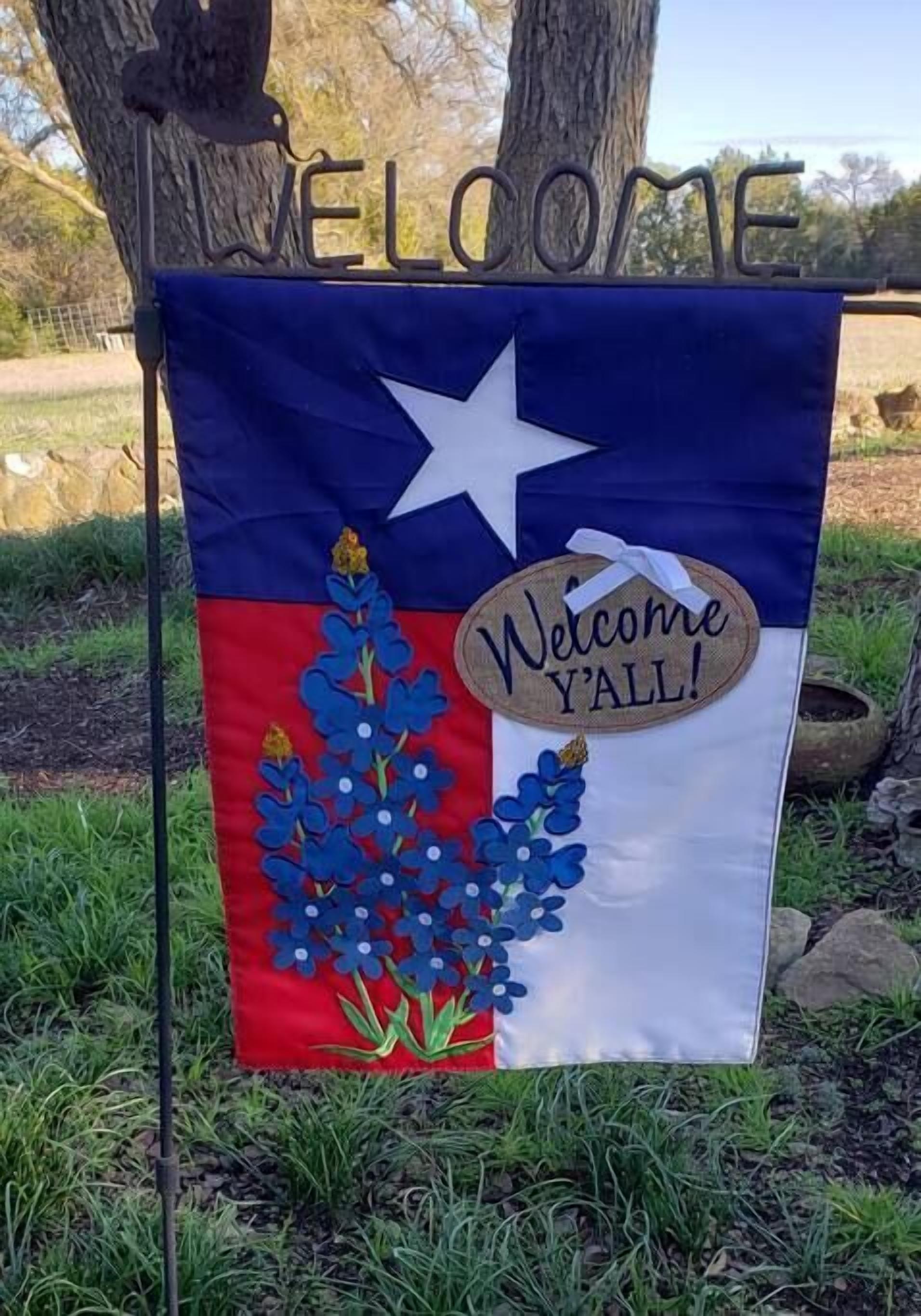 Uma bandeira com o desenho do estado do Texas, uma grande estrela e um letreiro que diz 'Welcome Y'all!'.