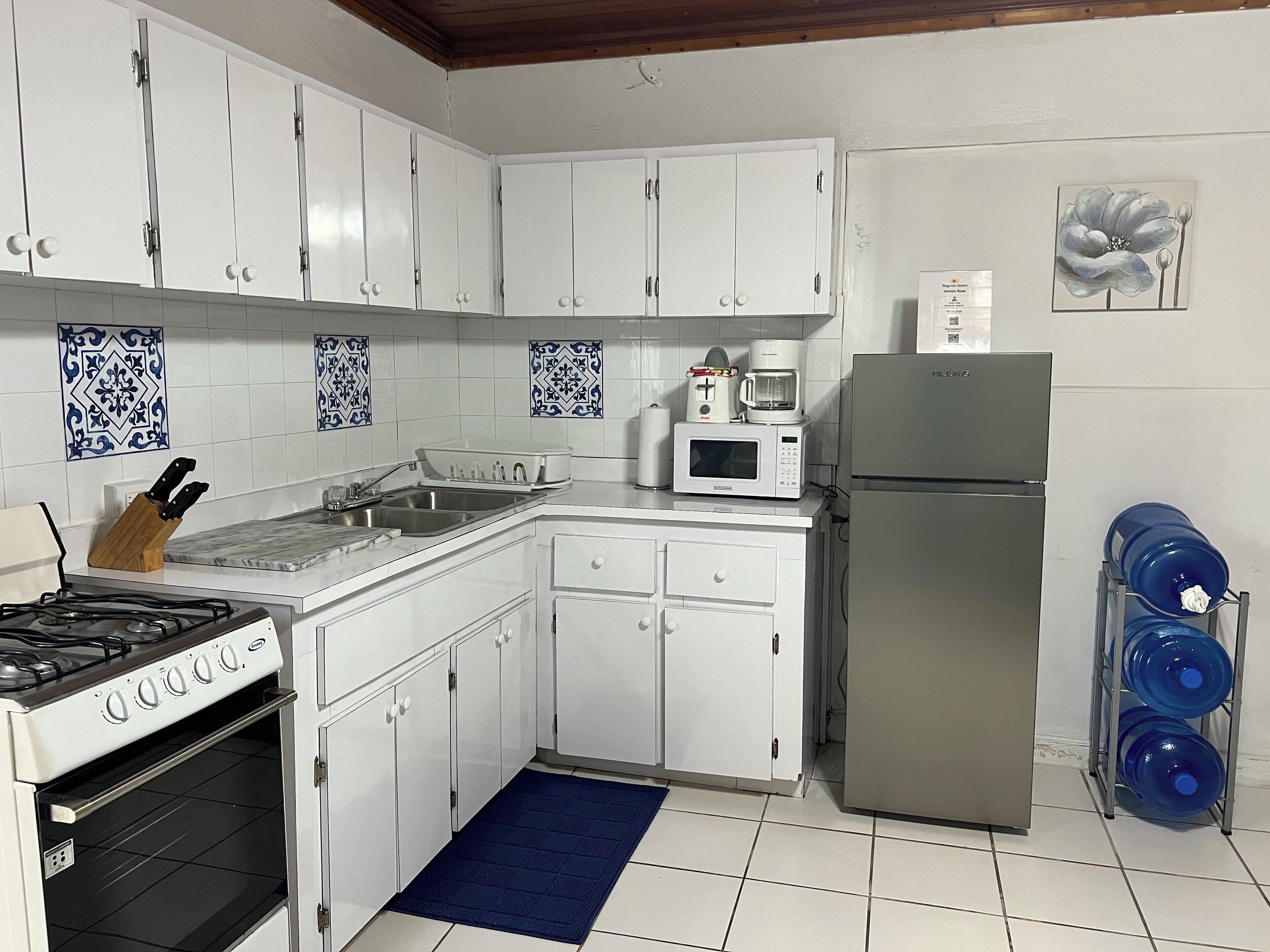 A kitchen with white cabinets, a gas stove, a microwave, and a refrigerator.