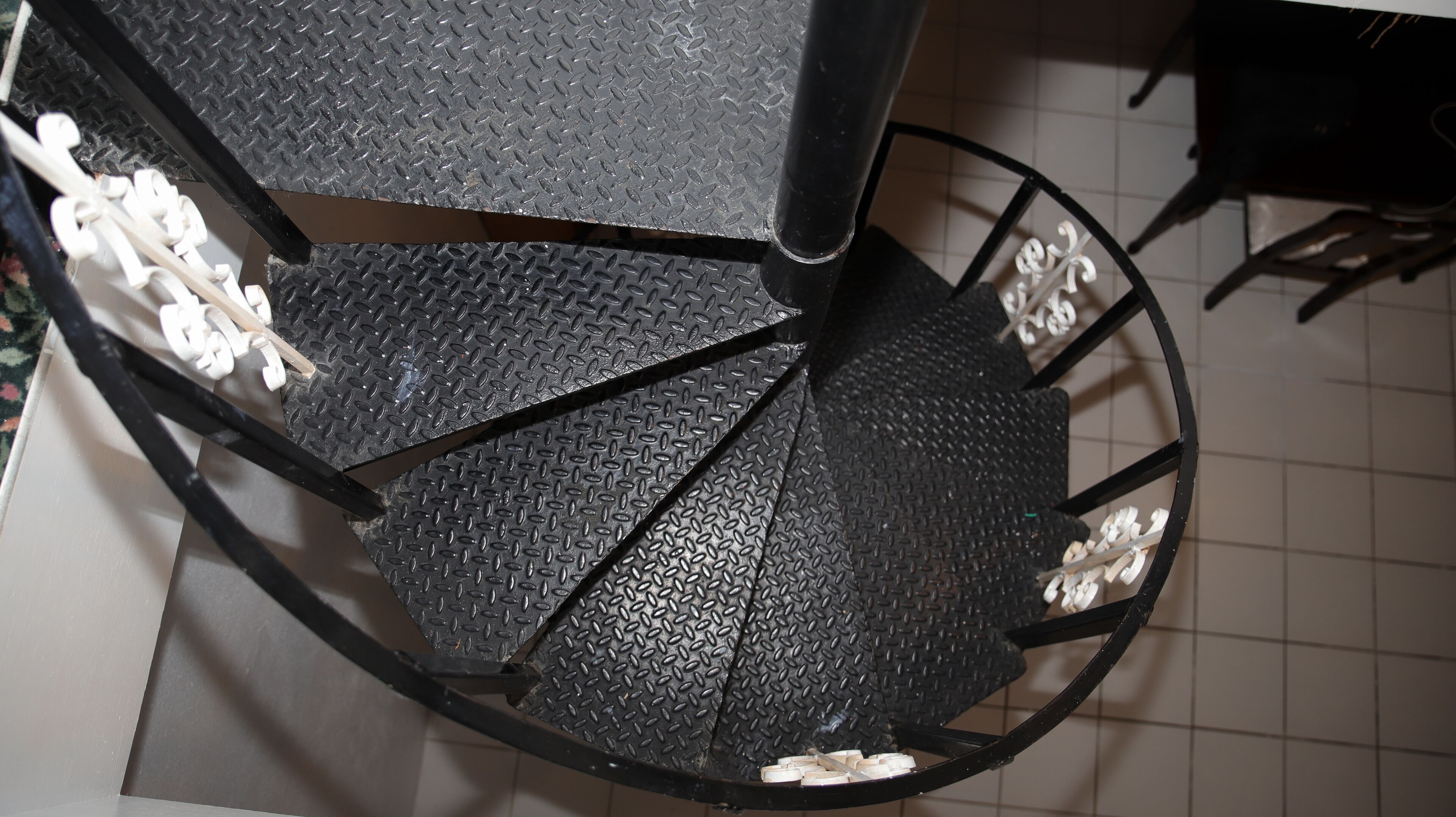 A spiral staircase with a black metal finish and a diamond plate pattern.