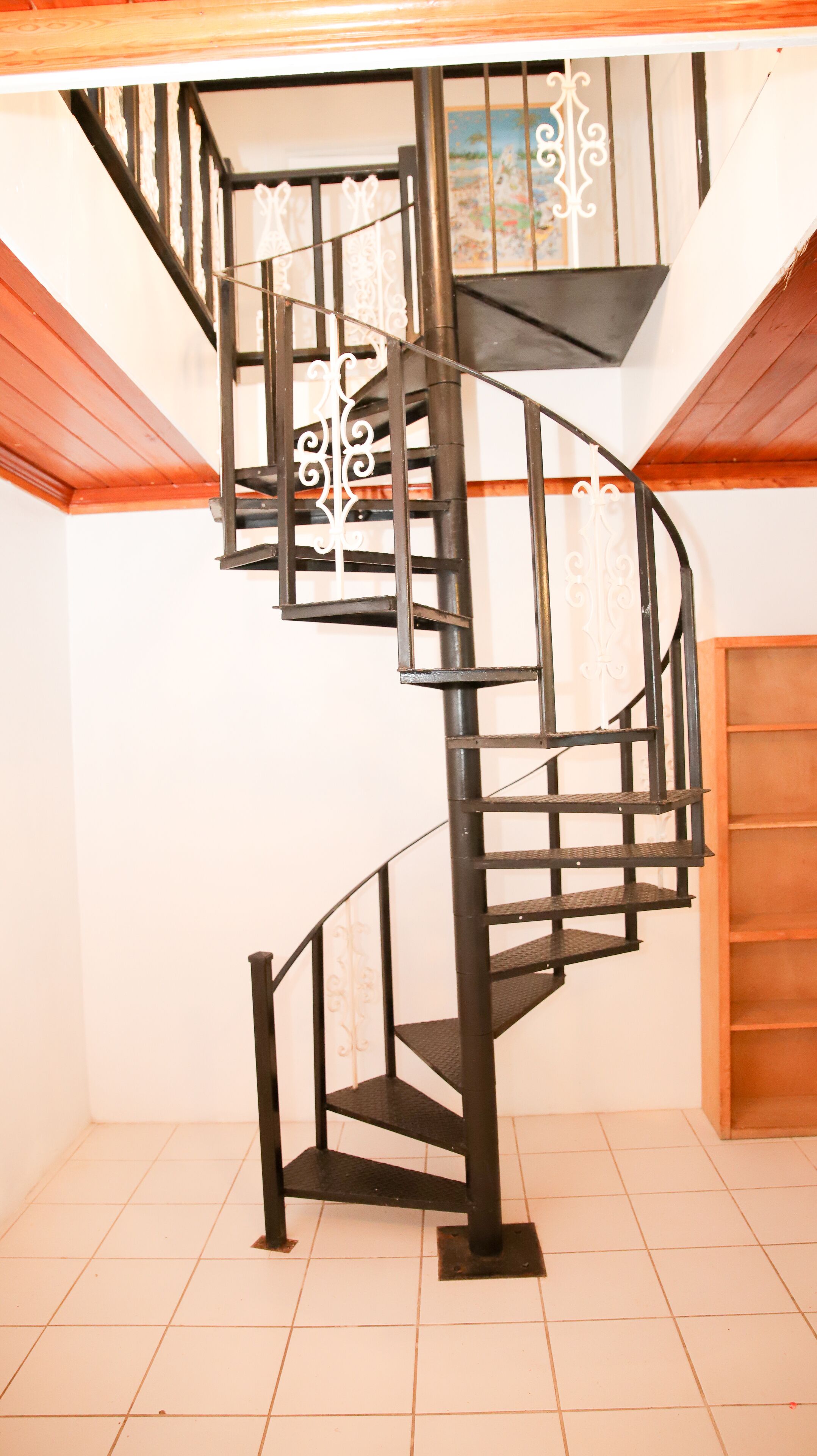 A spiral staircase with black metal railings and a wooden finish on the walls.