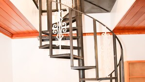 Eine Wendeltreppe mit schwarzen Metallgeländern und einer Holzvertäfelung an den Wänden.