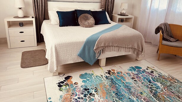 Ein Schlafzimmer mit einem Bett, Nachttischen, einem Sessel und einem bunten Teppich.