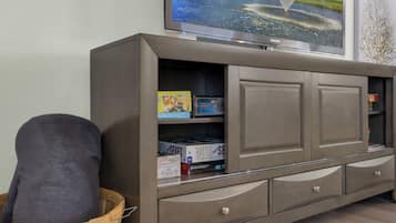 Een grijze entertainmentkast met een flatscreen televisie, een mand en gezelschapsspellen.