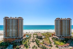 Um hotel à beira-mar com dois edifícios altos, uma área de piscina e vista para a praia.