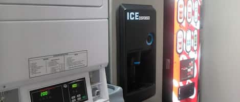 Un cuarto de lavandería con lavadora, dispensador de hielo y máquina expendedora de Coca-Cola.