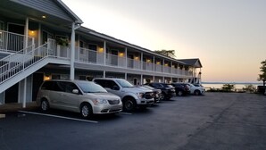 Et motel med parkerede biler, et overdækket område og udsigt til vandet.