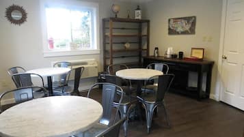 A dining area with two round tables and six chairs, a bookshelf, and a door.