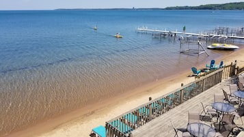 A beach with clear water, a dock, and outdoor seating.