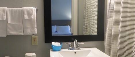 A bathroom with a white sink, a mirror, a toilet, and a shower curtain.