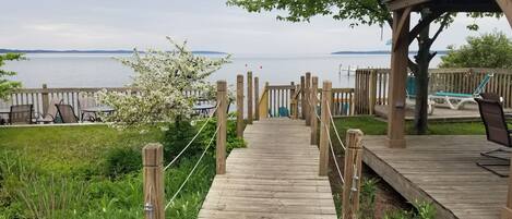 Una terraza de madera que conduce a la orilla, con vista al agua y a la costa distante.