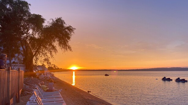 En strand med liggestole og en solnedgang over vandet.