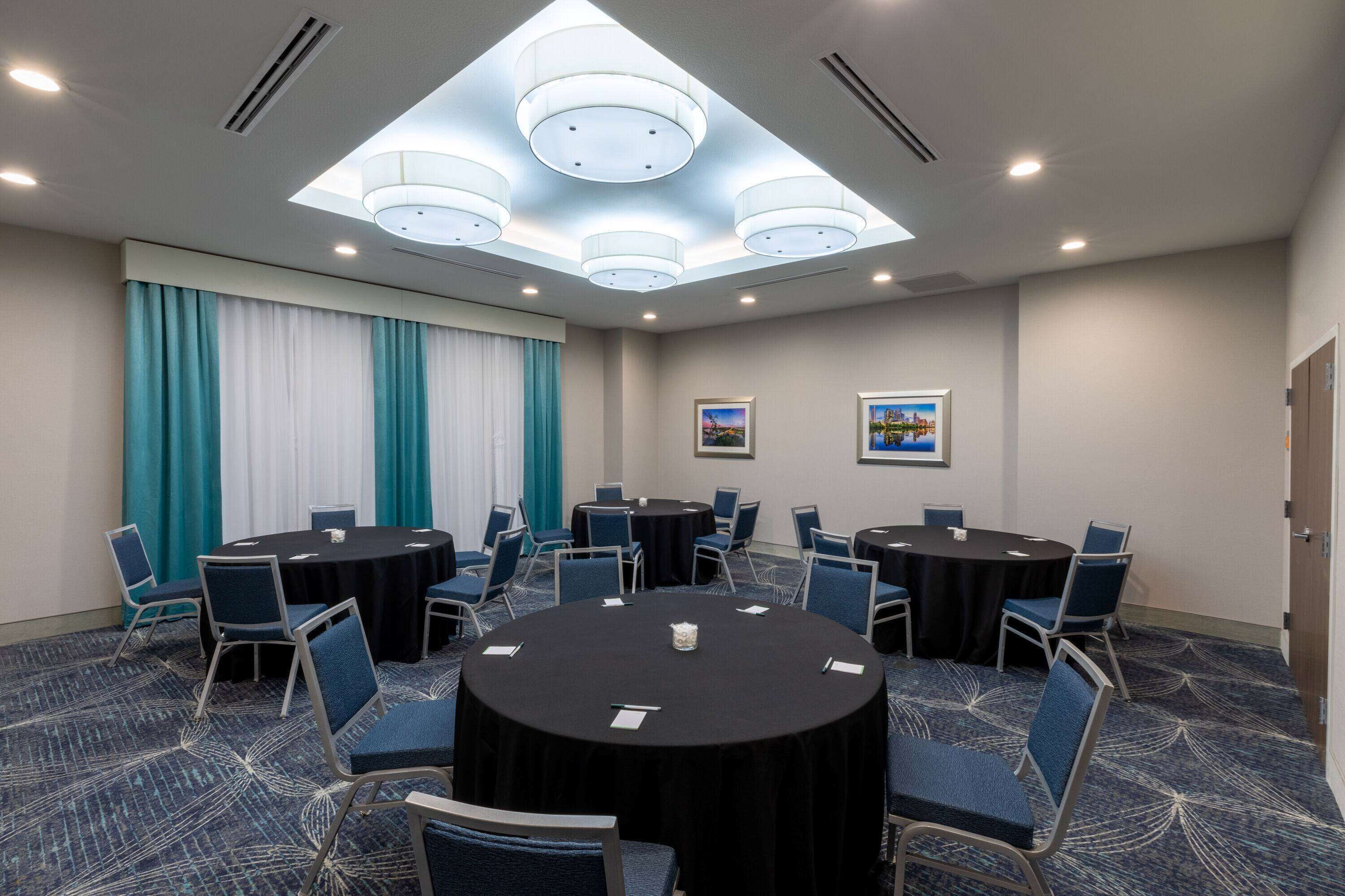 A conference room with round tables, blue chairs, and a patterned carpet.