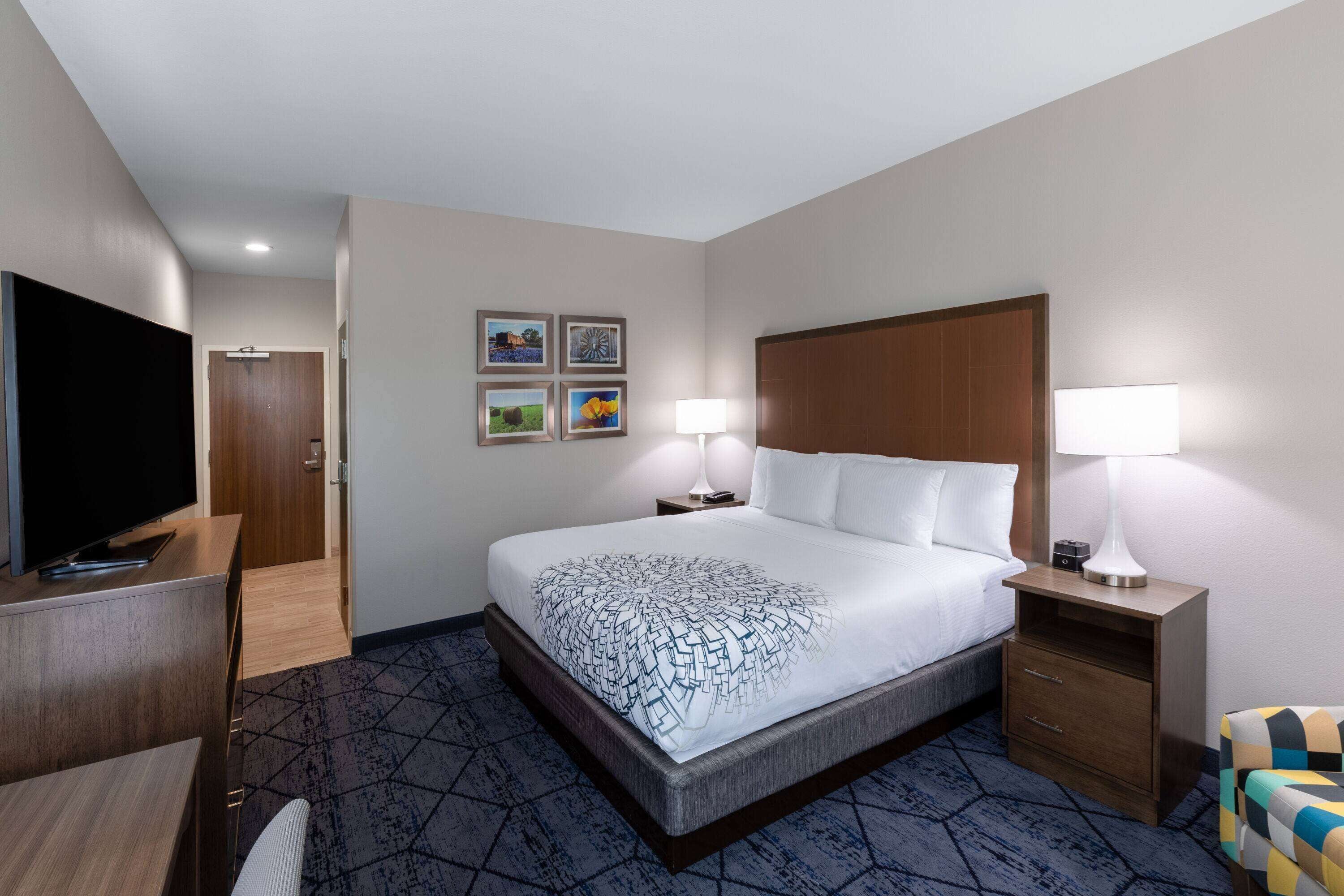 A hotel room with a bed, a TV, a desk, and a chair.