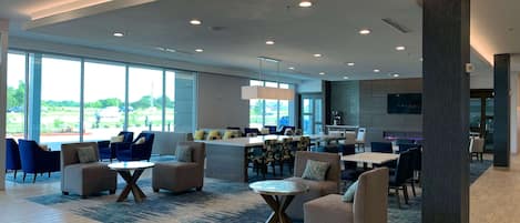 A spacious lobby with comfortable seating, large windows, and a modern ceiling design.
