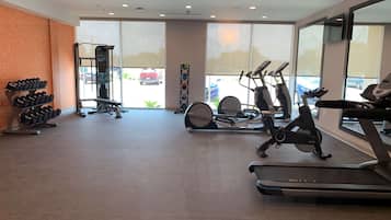 Un gimnasio con cintas de correr, elípticas y equipo de levantamiento de pesas.