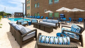 A poolside area with lounge chairs, a sofa, and umbrellas. - La Quinta Inn & Suites by Wyndham Round Rock near Kalahari (Round Rock)