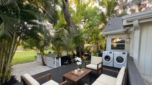 A deck with wooden furniture, a washing machine, and a white fence.