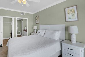 Une chambre à coucher bien aménagée, avec un grand lit, des tables de chevet et un ventilateur de plafond.