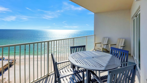Een balkon met een tafel en stoelen, met uitzicht op de oceaan.