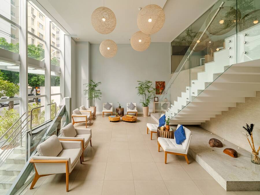 A spacious lobby with a modern staircase, comfortable seating, and large windows offering a view of the street.