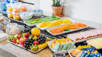 Una mesa de buffet con diversas frutas, verduras y aperitivos envasados.