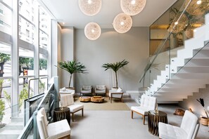 Un interior moderno con una escalera, muebles blancos y ventanas amplias.