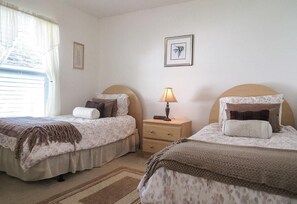 A bedroom with two beds, a nightstand, a lamp, and a framed picture on the wall.
