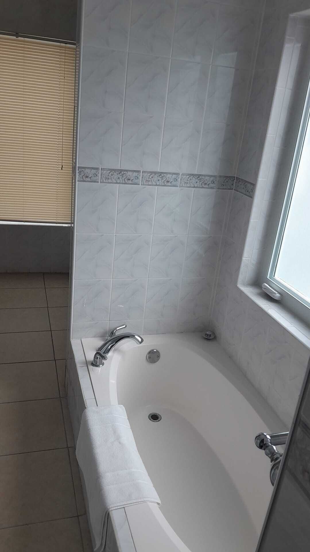A bathroom with a freestanding bathtub, a window, and a shower area.