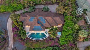 An aerial view of a property with a swimming pool, solar panels, and lush landscaping.