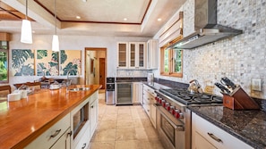 A modern kitchen with a large island, stainless steel appliances, and a backsplash of mosaic tiles. - Oceanview, Private Pool and Hot Tub! (Launiupoko)