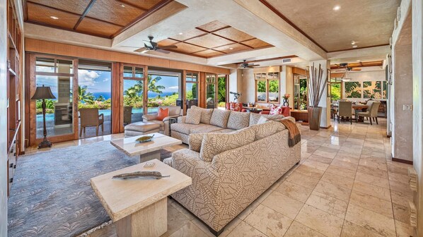 A spacious living area with a large sofa, a coffee table, and a dining area with chairs.