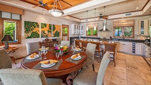 A spacious dining area with a round table set for a meal, surrounded by comfortable chairs.