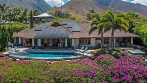 Ein Haus mit Swimmingpool, Solaranlage und einer Bergkulisse.