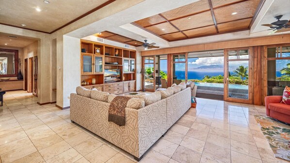 A spacious living area with a large sofa, a television, and a view of the ocean.