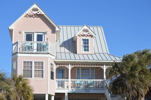 A two-story building with a balcony and a small attached structure. - Ocean View Third Row Home (Oak Island)