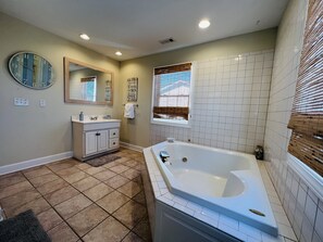 A bathroom with a bathtub, vanity, mirror, and tiled walls. - Ocean View Third Row Home (Oak Island)