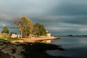 A lakeside property with a small dock, a grassy area, and a building with a white exterior. - Inn at Longshore (Westport)
