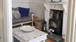 A living room with a white sofa, a blue cushion, a white coffee table, a fireplace, and a large mirror.