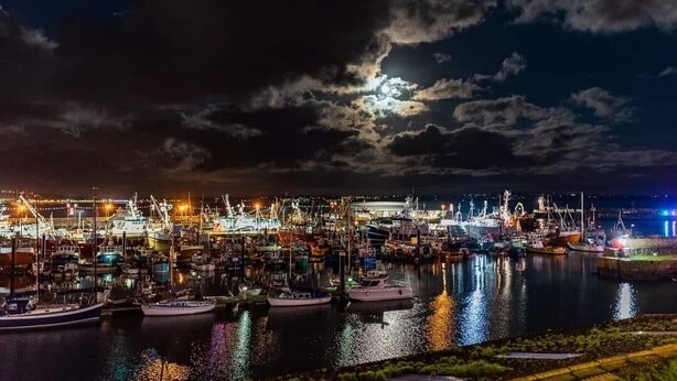 A marina at night with boats docked and illuminated by artificial lights.