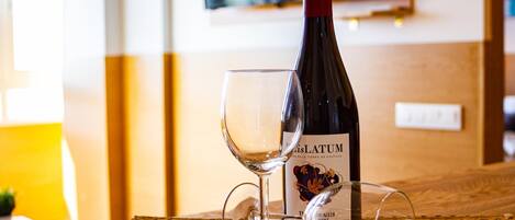 A bottle of wine and two glasses on a woven placemat.