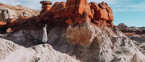 A desert landscape with rock formations and a person standing in the foreground.