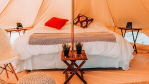 A tent with a bed, a small table, and a round ottoman. - Wander Camp Bryce Canyon - Escalante (Cannonville)