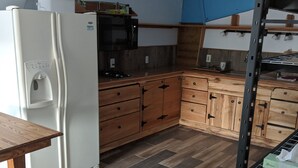 A kitchen with wooden cabinets, a white refrigerator, and a microwave. - Nice apartment in shop with Indoor parking for toy trailers or vehicle. (THAYNE)