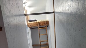 A narrow hallway with a bunk bed, wooden ladder, and patterned rugs. - Nice apartment in shop with Indoor parking for toy trailers or vehicle. (THAYNE)