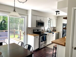 Een moderne keuken met witte kasten, roestvrijstalen apparatuur en een houten aanrecht.