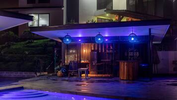 Uma casa moderna com piscina, área de estar externa e um pátio bem iluminado.