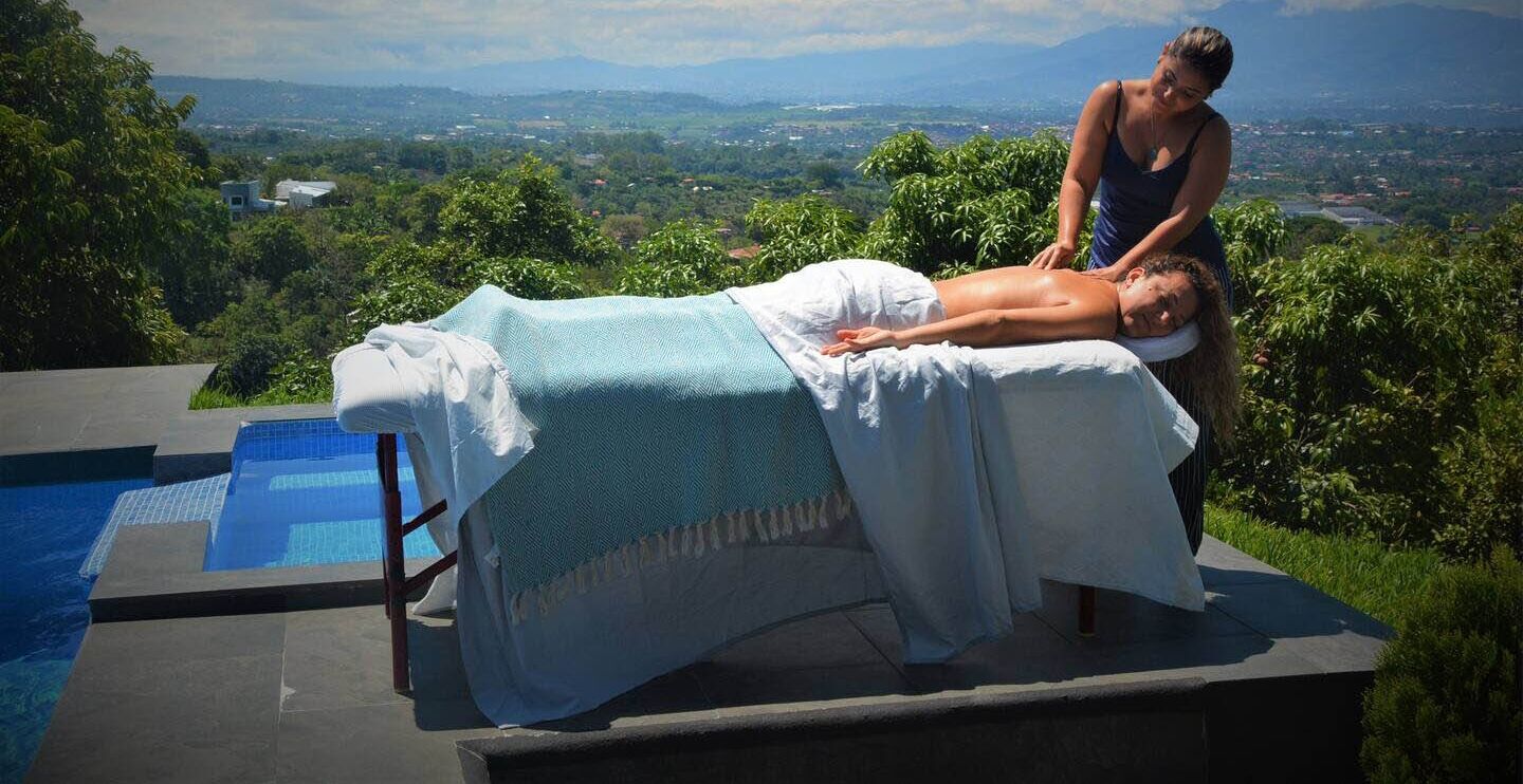 A massage therapy session in a poolside setting with a view of a cityscape.