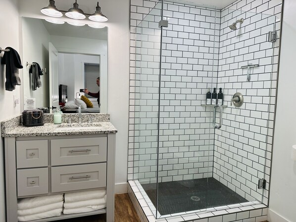 A bathroom with a shower, a sink with a mirror, and a towel rack.