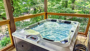 Un bain à remous sur une terrasse en bois, avec vue sur une forêt.