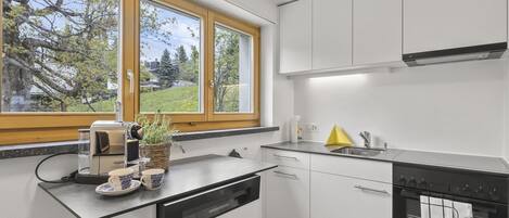 Kjøleskap, oppvaskmaskin, høy barnestol og kjøkkenutstyr